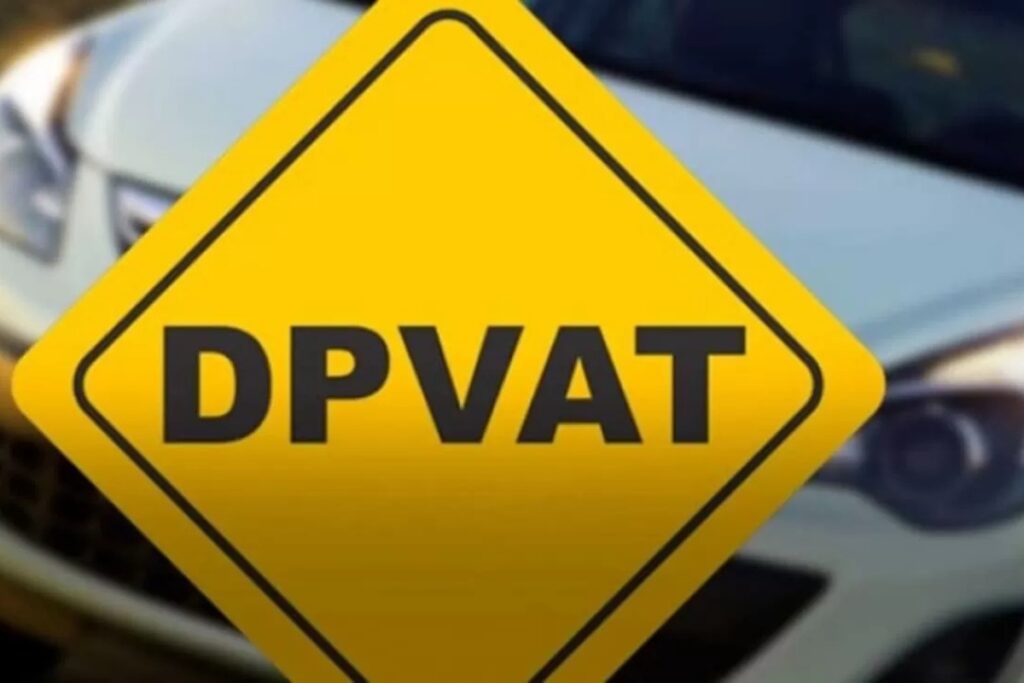 Placa amarela com texto DPVAT, carro ao fundo.