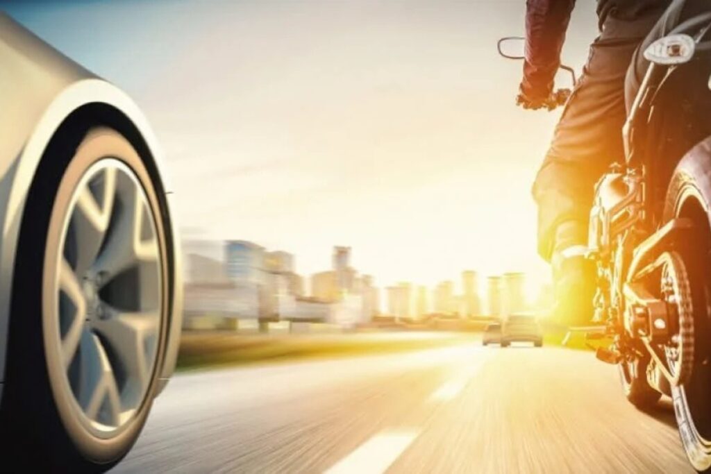 Car and motorcycle speeding on highway at sunset